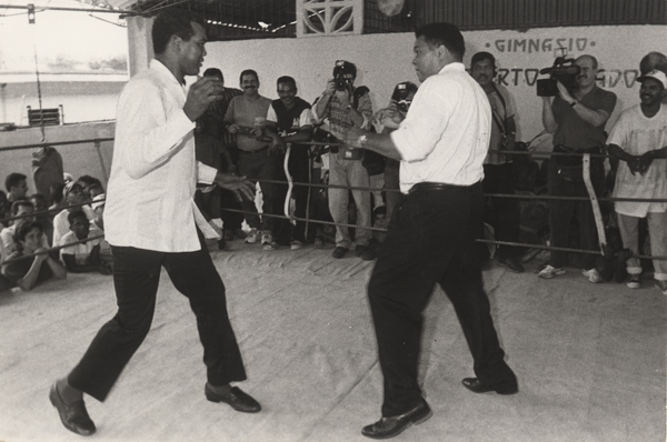 Cuban boxer Teófilo Stevenson and heavy weight champion Muhammad Ali on the boxing ring in front of fans.